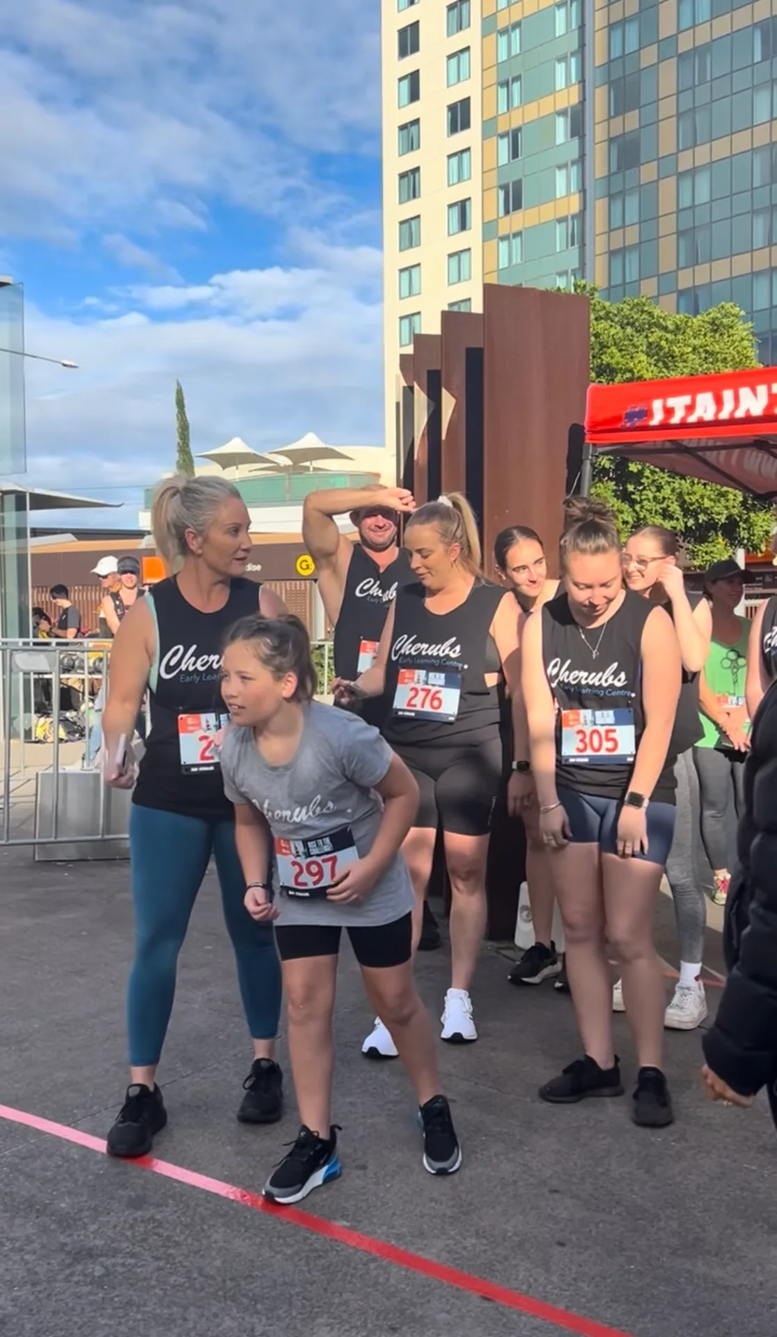 The Cherubs team in matching singlets with race bibs, waiting at the start line of the Q1 Stair Challenge