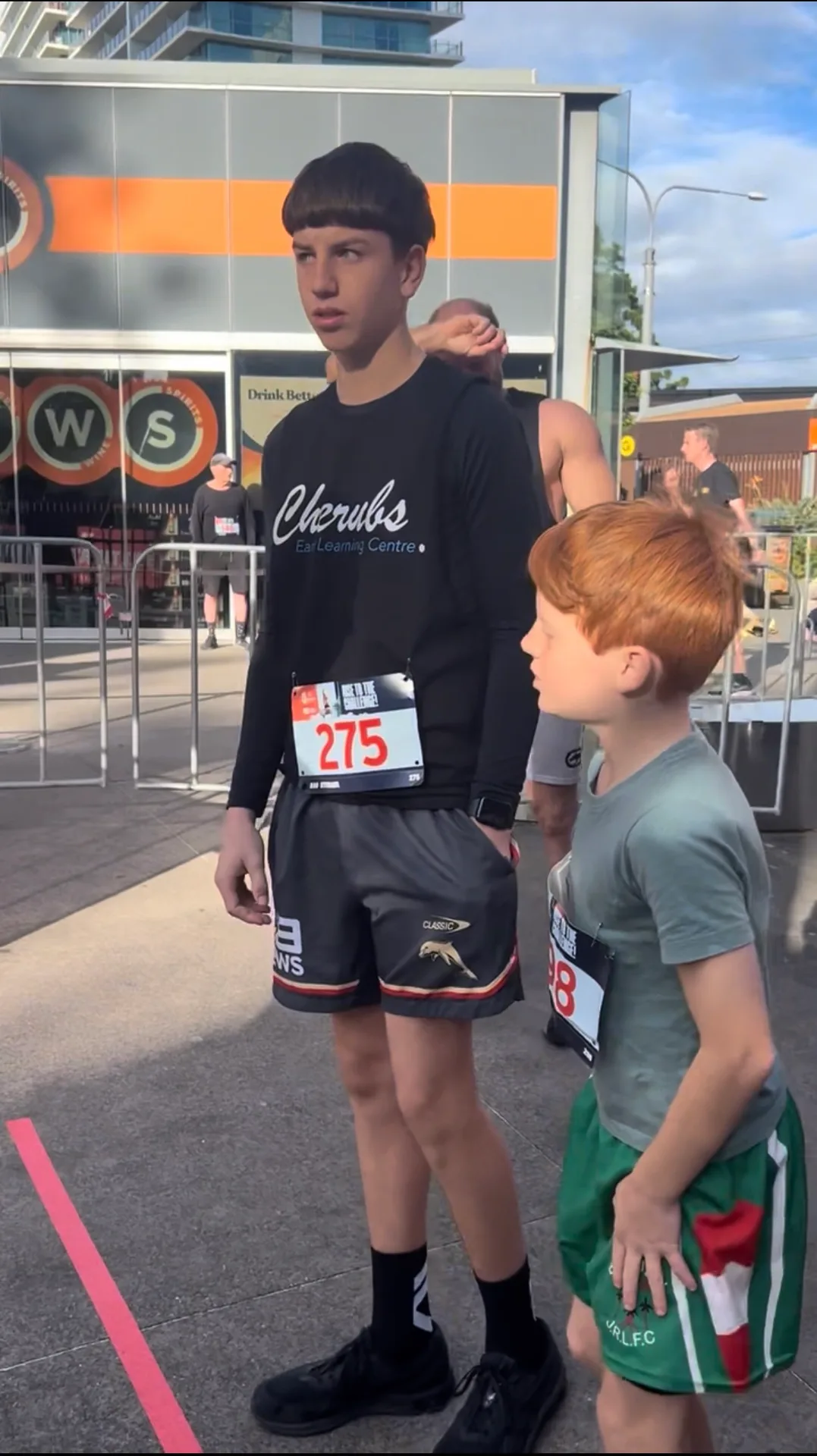 A young Cherubs climber in a Cherubs long-sleeve top with race bib 275 before the Q1 Stair Challenge