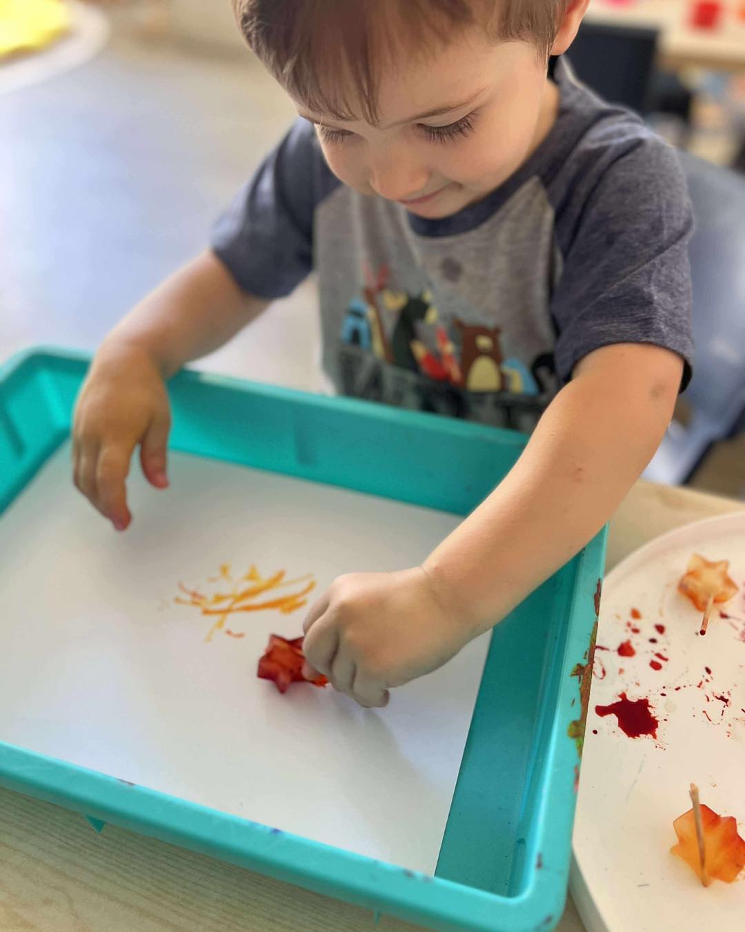 A toddler painting on a tray at Cherubs Banora Point